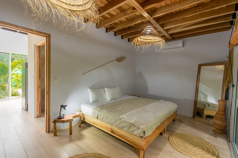 Habitación planta baja — cama king con vigas de madera al descubierto
